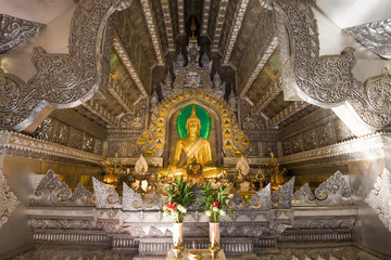 Altar of the old Silver Temple (Wat Sri Suphan) with a golden sculpture of a seated Buddha close-up. Chiang Mai, Thailand