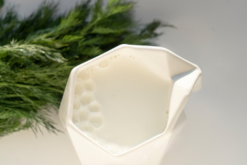 A mug of fresh milk, next to a bunch of greens. The view from the top