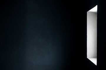 Light from the window to the wall of a gloomy room with concrete walls.