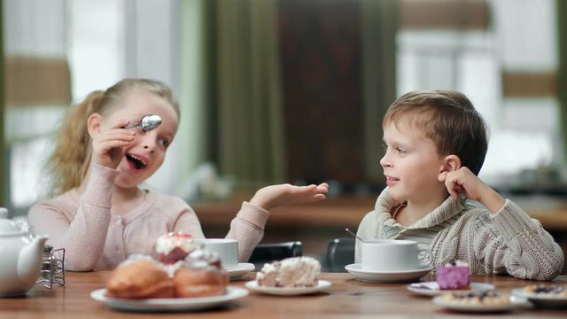 Funny children boy and girl talking smiling eat dessert and drink tea at cafe. 4k Dragon RED camera