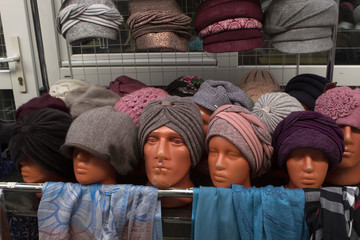 male mannequin in women's clothing. a lot of multi-colored women's knitted hats on the shop window...