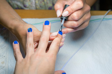Beautiful manicure process. Nail polish being applied to hand, polish is a blue color. close up