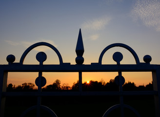 Silhouetted gate with wrought iron elements at sunset