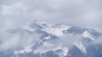 Fototapeta na wymiar Snow capped mountain peak in the clouds
