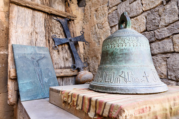 Obraz premium Bell, cross and hammered crucifix on background of masonry and an old wooden shield on handmade rug