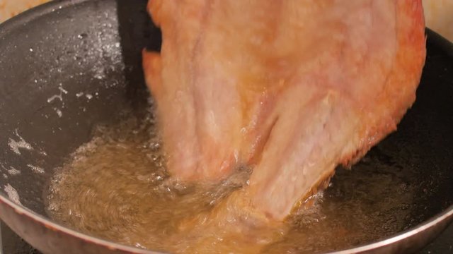 Flip the fried snapper with fish sauce in the black pan. And the hot oil is boiling