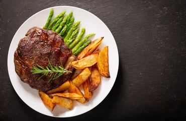 Foto op Canvas plate of grilled steak with rosemary, asparagus and potato, top view © Nitr