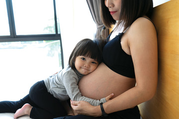 Asian cute girl hug tummy mummy smile face.