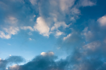 Naklejka na ściany i meble Blue sky with contrasting light and dark cumulus clouds. Sky pattern.