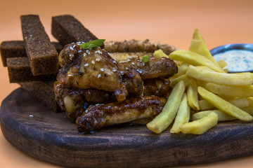 View of pieces of fried chicken and fried potato wedges. Bread croutons in the background