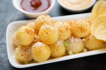 Close-up of potato balls topped with parmesan cheese, selective focus, horizontal shot