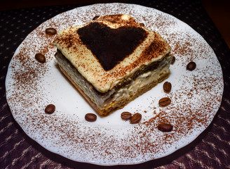 Nicely plated tiramisu cake with sprinkled cocoa and coffee beans