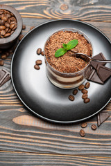 Classic tiramisu dessert in a glass cup on wooden background