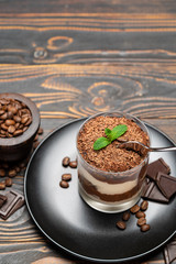 Classic tiramisu dessert in a glass cup on wooden background