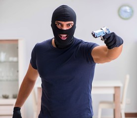 Robber wearing balaclava stealing valuable things