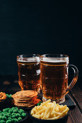 Beer and salty snacks. table with two mugs of craft lager and crunchy appetizers. Oktoberfest food, pub concept