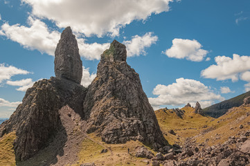 Fototapeta na wymiar Unrecognizable man at the base of Old man of Storr rock formations, Isle of Skye, Scotland. Concept: typical Scottish landscape, tranquility and serenity, particular morphologies