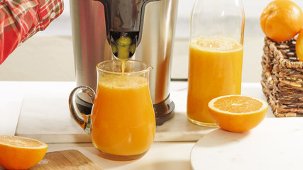 Fresh orange juice in a glass jug close up on white background. Preparing fresh orange juice using...