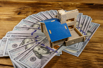 House model and U.S. one hundred dollar bills on wooden background. Property investment, home loan, house mortgage, real estate concept