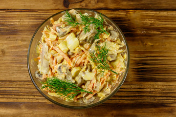 Tasty salad with chicken breast, roasted mushrooms, carrots, grated cheese, eggs and mayonnaise on wooden table. Top view