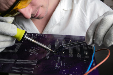 The master solders the part with a soldering iron to the motherboard