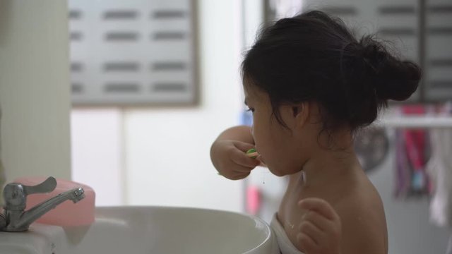 Asian child cute or kid girl brush teeth by toothbrush with toothpaste and themselves for clean and learning in basin to prevent tooth decay and fluoride coating with white teeth for dental on 4K