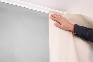 A man glues wallpaper in the room. Repair, construction and home concept.