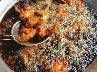 Chicken frying in a pan, chicken deep frying in oil in a cast iron frying pan