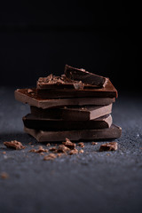 Piece of dark chocolate and chocolate chips on a dark background