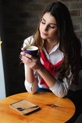 Girl at a table by the window in a cafe with a cup of coffee