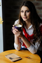 Girl at a table by the window in a cafe with a cup of coffee