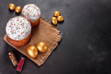 Easter eggs gold and bronze and Easter cake on a dark background