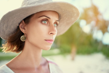 Vacation and natural beauty. Close up outdoor portrait of pretty tanned young woman in hat.