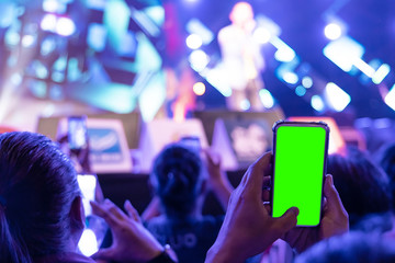 Hands of audience crowd people taking photo with mobile smart phone with green screen in party concert.