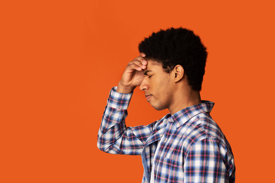 Stress, lack of inspiration or depression. African-American man thinking on color background, side view. Copy space