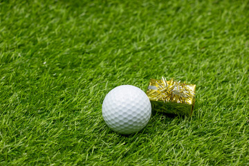 Golf ball with gift on green grass