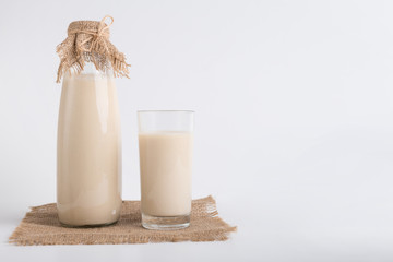 Soy milk in bottle and glass on linen cloth