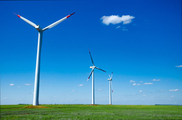 Fototapeta premium Wind turbines on green field blue sky clouds green energy concept renewable energy generator