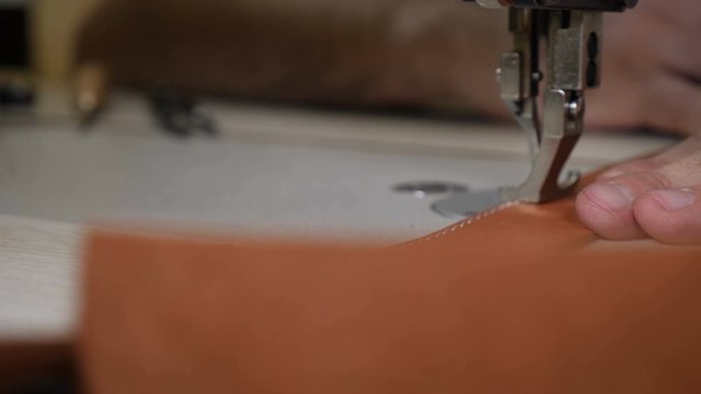 Close-up macro view of sewing machine in leather manufacture, sew leather for belt, bag or wallet. workshop by handmade artisan expert in manufacturing leather belts, manufacture. traditional