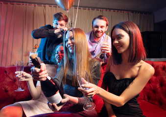 enjoyment and leisure. young caucasian people gathered to have party in karaoke bar, drinking...
