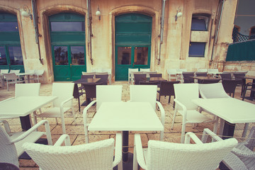 Sidewalk cafe near ancient bulding with green wooden windows.