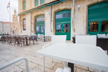 Sidewalk cafe near ancient bulding with green wooden windows.