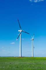 Fototapeta premium Wind turbines on green field blue sky clouds green energy concept renewable energy generator