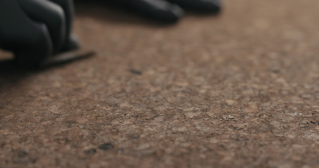 man hands in black gloves sand dark cork surface