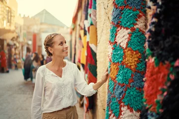 Zelfklevend Fotobehang Reizen en winkelen. Jonge reizende vrouw met kies cadeautjes in Souvenirwinkel in Marokko. © luengo_ua