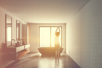 Woman in pajamas in white sunlit bathroom