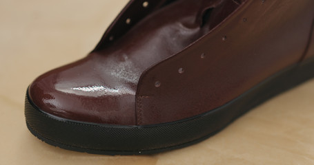 spraying water protection spray on brown leather sneakers