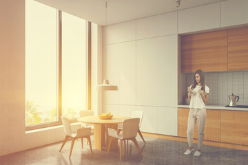 Woman in white and wood kitchen corner with table