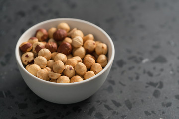 roasted hazelnuts in white bowl on concrete background