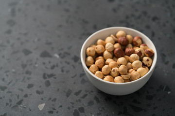 roasted hazelnuts in white bowl on concrete background